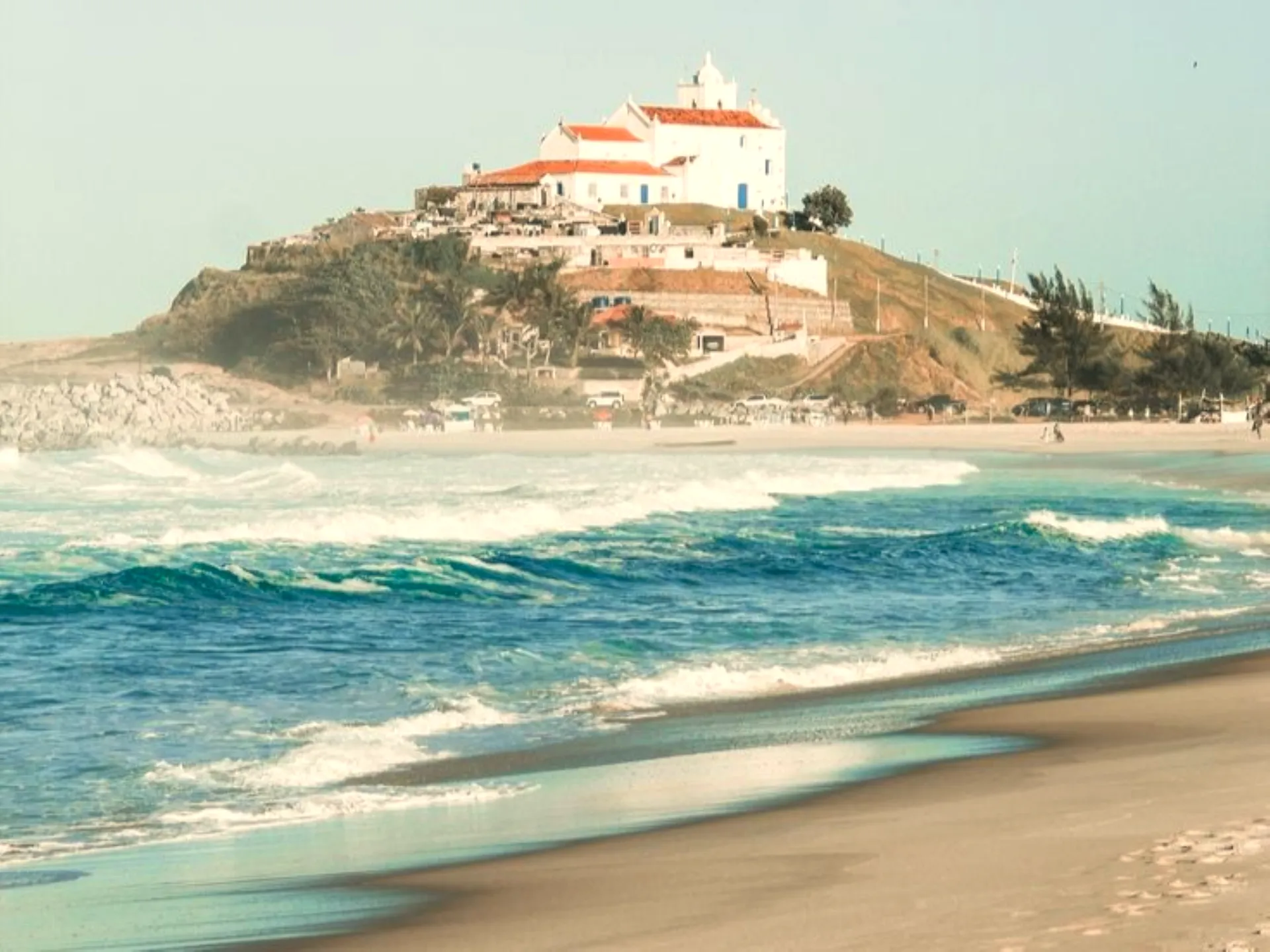 A praia de Itaúna com a Igreja de Nossa Senhora de Nazareth no morro, em Saquarema